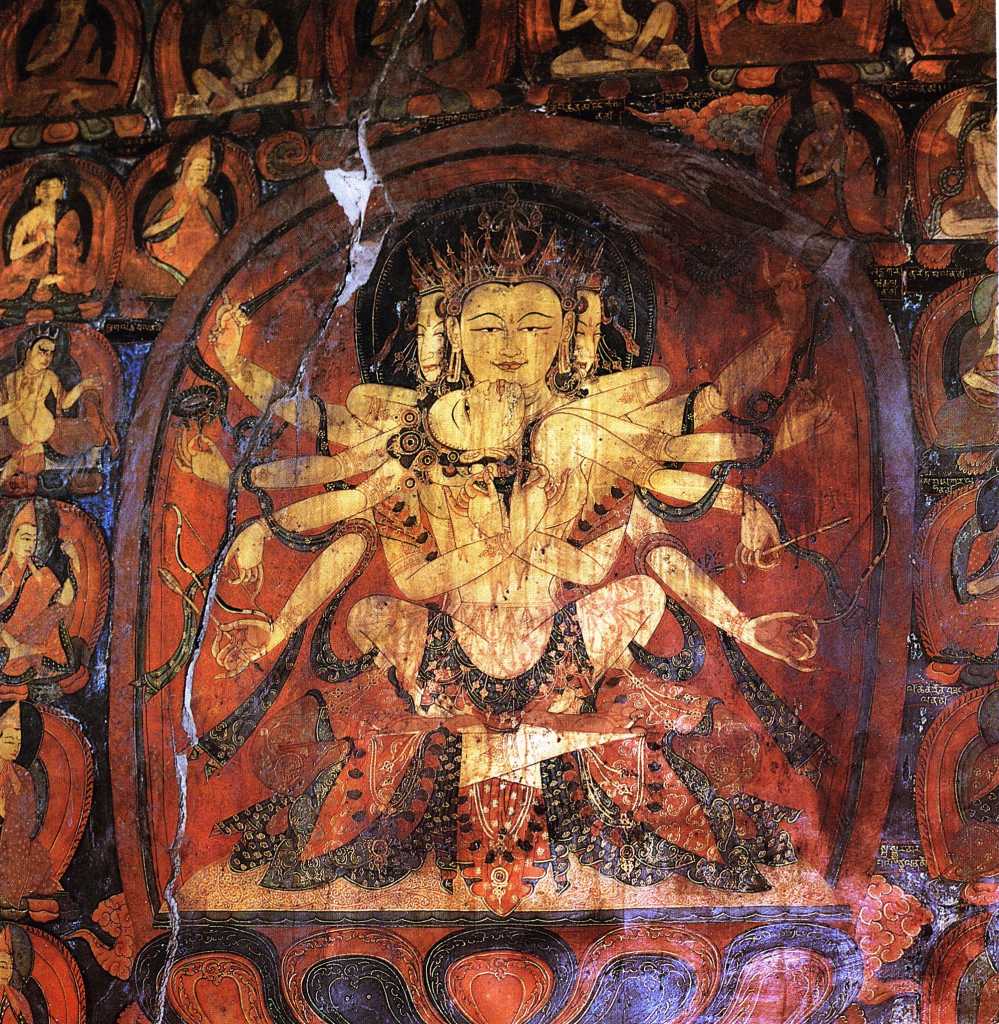 Tibet Guge 08 Tsaparang 03 Yamantaka Temple Guhysamaja-Manjuvajra On the left wall in yab-yum with his consort Sparshavajra are three paintings of the three-faced six-armed Guhyasamaja, Guhyasamaja-Manjuvajra and Guhyasamaja-Akshobyavajra, associated with the Buddha Akshobhya, and the most ancient and fundamental Tantra of Vajrayana tradition of Buddhism. Here is Guhyasamaja-Manjuvajra with his two central hands crossed near the centre of his body, his right hands holding a sword and arrow, and his left holding a lotus and bow. Sparshavajra�s two main hands circle Guhyasamaja- Manjuvajra, while her other hands mirror his. Photo: Weyer/Aschoff: Tsaparang, Tibets Grosses Geheimnis
